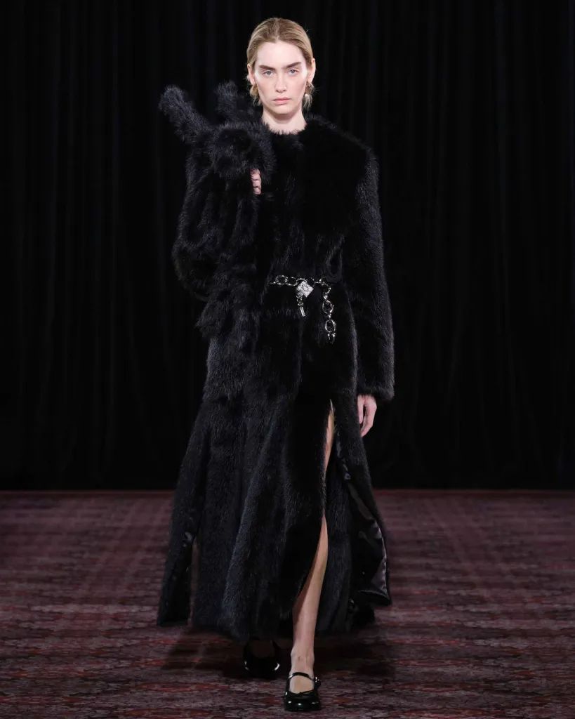 Simone Rocha AW25 runway look: long black faux fur coat with chain belt